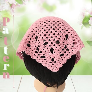 Puede incluir: Una diadema de crochet rosa con un delicado patrón floral. La diadema se lleva en un maniquí con el pelo negro corto.