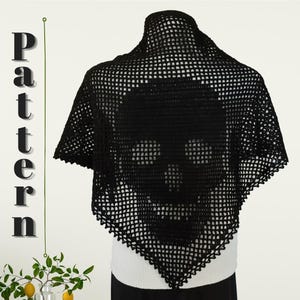 May include: Black crochet shawl with a skull design. The shawl is triangular in shape and features a large skull motif in the center. The edges are finished with a decorative trim. The word "Pattern" is written vertically on the left side of the image.