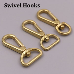 May include: Three gold swivel hooks. The hooks are made of metal and have a smooth, polished finish. They are designed to be attached to bags, belts, or other items.