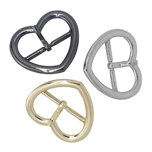 Op de afbeelding: Drie hartvormige metalen gespen in goud, zilver en zwart.