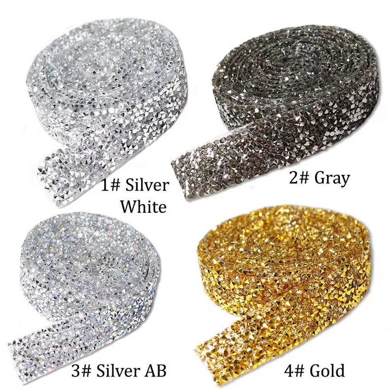 May include: Four rolls of rhinestone trim in different colors: silver white, gray, silver AB, and gold. Each roll is approximately 1 yard long and 1 inch wide.