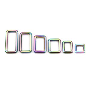 Peut inclure: Un ensemble de six anneaux en D métalliques irisés de différentes tailles. Les anneaux sont de forme rectangulaire et ont une finition lisse et polie.