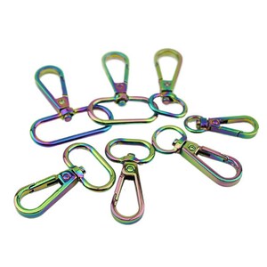May include: A set of eight rainbow-coloured metal swivel clasps. The clasps are oval-shaped with a hook on one end and a loop on the other. They are perfect for attaching to bags, keychains, or other accessories.