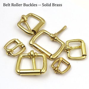 May include: A set of five gold-toned metal belt roller buckles. The buckles are all different sizes and have a square shape with rounded corners. The buckles are made of solid brass.