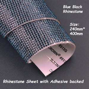 Può includere: Un rotolo di foglio di strass blu e nero con retro adesivo. Il foglio misura 240 mm per 400 mm ed è etichettato "#513G CROWN® #513".