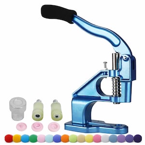 Puede incluir: Máquina azul para colocar broches con un mango negro y una variedad de broches de colores. La máquina tiene una palanca y un mecanismo de resorte. Incluye varios componentes y una selección de broches coloridos.