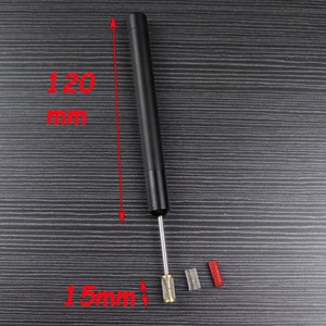 Peut inclure: Un outil en m&eacute;tal noir avec une pointe rouge, mesurant 120 mm de long et 15 mm de diam&egrave;tre. L'outil est accompagn&eacute; de deux petites brosses cylindriques rouges.
