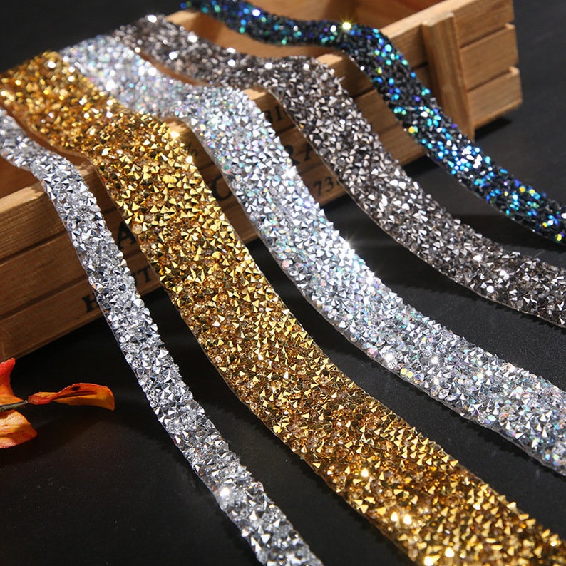 May include: Five rolls of rhinestone trim in different colors, including silver, gold, and iridescent. The trim is made of small, faceted rhinestones that are sewn onto a clear, flexible backing.