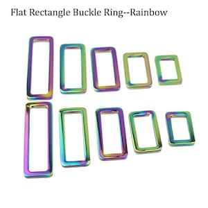 May include: A collection of flat, rectangular buckle rings in various sizes. The rings have a rainbow iridescent finish, displaying a spectrum of colors including purple, green, and gold. The text "Flat Rectangle Buckle Ring--Rainbow" is at the top.