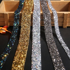 May include: Five rolls of sparkly trim with a diamond-like pattern. The trim is available in black, gold, silver, gray, and clear.