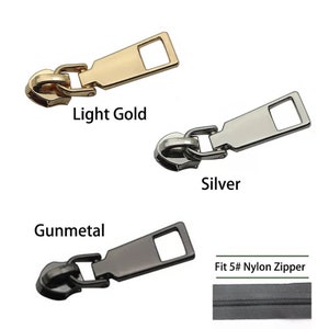 May include: Three zipper pulls in light gold, silver, and gunmetal finishes. The zipper pulls are designed to fit a #5 nylon zipper. A close-up of a #5 nylon zipper is shown below the zipper pulls.