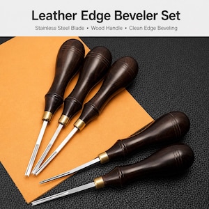 May include: A set of leather edge bevelers with dark wood handles and stainless steel blades. The image shows the tools arranged on a tan surface, with the text "Leather Edge Beveler Set" at the top.