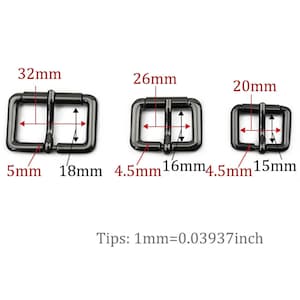 Może przedstawiać: Trzy czarne metalowe suwaki do klamer pasowych w r&oacute;żnych rozmiarach. Największa klamra ma 32 mm szerokości i 18 mm wysokości, środkowa klamra ma 26 mm szerokości i 16 mm wysokości, a najmniejsza klamra ma 20 mm szerokości i 15 mm wysokości.  Wskaz&oacute;wki: 1 mm = 0,03937 cala