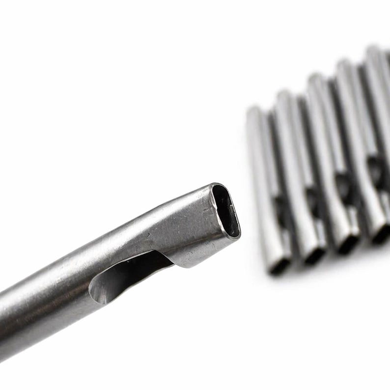 May include: Close-up of several silver-colored metal tubes with a rectangular opening. One tube is in focus, showing a side opening. The tubes are arranged against a white background.