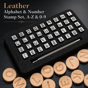 Pode incluir: Um conjunto de carimbos de couro com alfabeto e números (A-Z e 0-9), apresentado numa caixa de espuma preta. O conjunto inclui uma pega de metal, ideal para trabalhos em couro. Círculos de couro estampados também são visíveis.