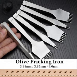Puede incluir: Un conjunto de punzones de costura de cuero plateados, llamados "Olive Pricking Iron", con varias configuraciones de púas. La imagen incluye el texto "Olive Pricking Iron" y medidas de 3,38 mm, 3,85 mm y 4,0 mm.