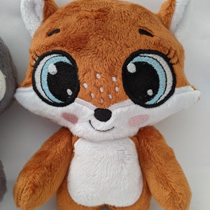 May include: A plush fox toy with large blue eyes and a white belly. The fox is brown and has a stitched smile.