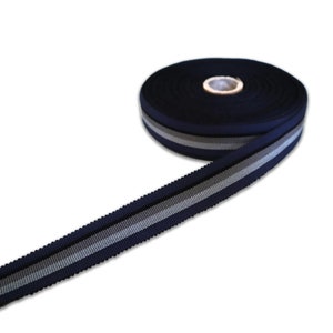 May include: A roll of navy blue ribbon with two silver stripes. The ribbon is approximately 2.5 cm wide.