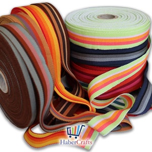 May include: Assortment of striped ribbon rolls in various colours, including green, orange, red, brown, and grey. The ribbon is woven with a textured pattern. HaberCrafts logo is visible in the bottom right corner.
