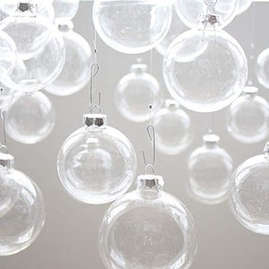May include: A collection of clear glass ornaments hanging from silver hooks. The ornaments are various sizes and are all transparent.