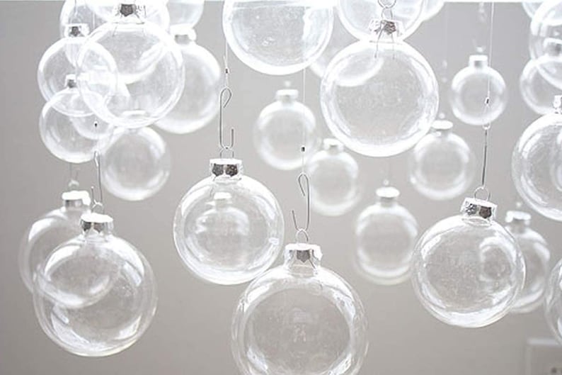 May include: A collection of clear glass ornaments hanging from silver hooks. The ornaments are various sizes and are all transparent.