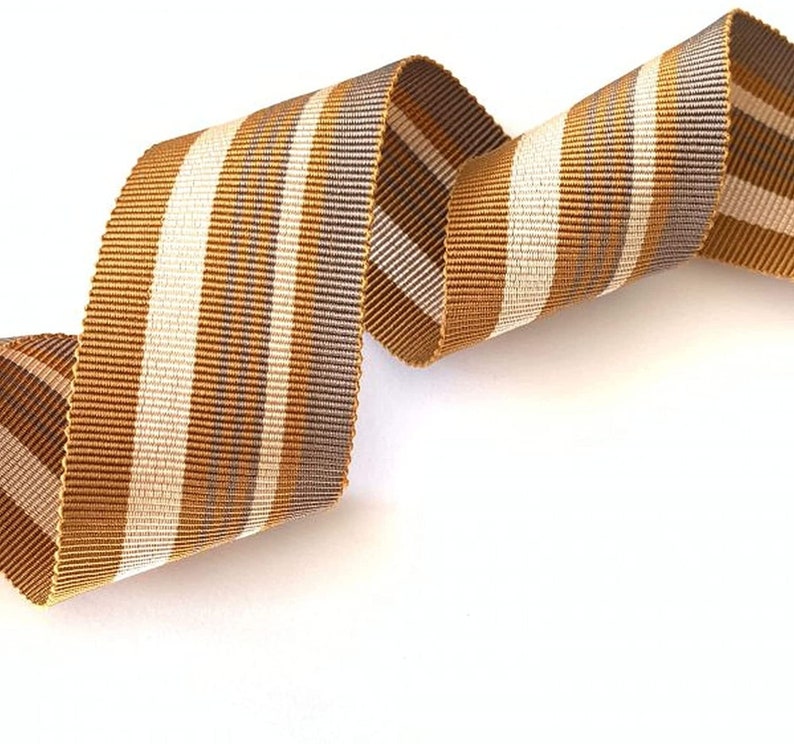 May include: A brown and white striped ribbon with a subtle shimmer. The ribbon is curled and twisted, showing off its texture.