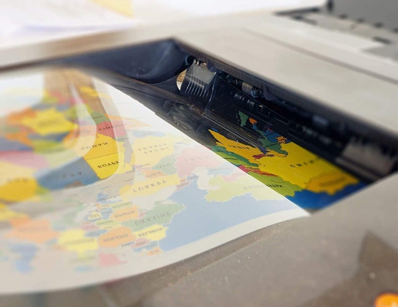 May include: A close-up of a flatbed scanner with a colorful world map being scanned. The map is yellow, blue, green, and red. The scanner is white and gray.