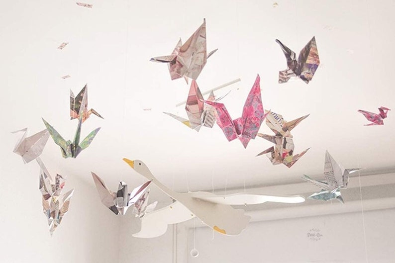 May include: A white paper swan mobile with colorful paper origami birds hanging from it. The mobile is made of paper and is a great addition to any nursery or child's room.