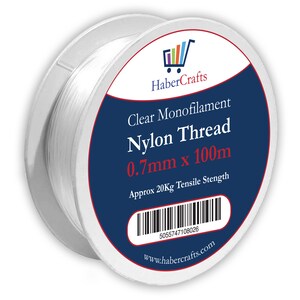 May include: A spool of clear monofilament nylon thread, 0.7mm thick and 100 meters long. The spool is labeled "Clear Monofilament Nylon Thread 0.7mm x 100m" and "Approx 20Kg Tensile Strength". The label also includes a barcode and the website "www.habercrafts.com".
