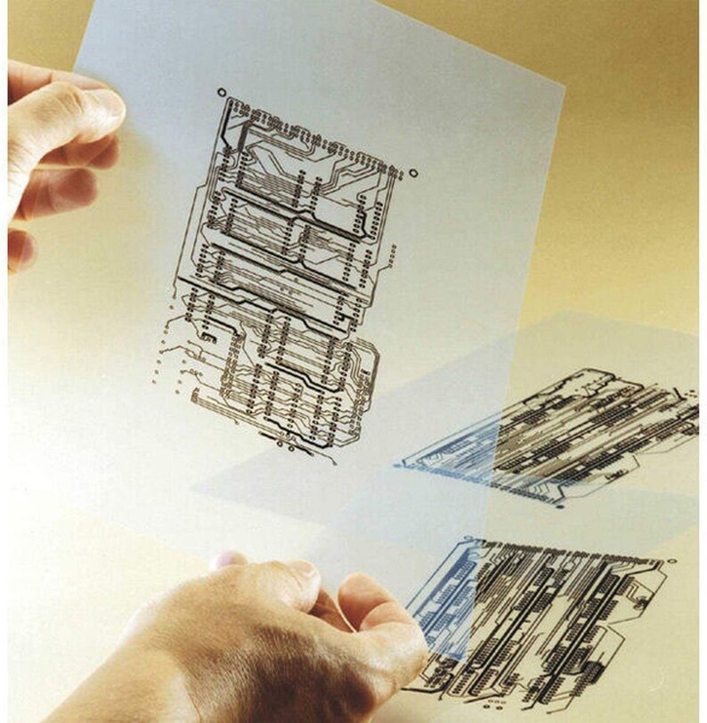 May include: A close-up of a person holding a transparent sheet with a black and white circuit board design printed on it. The sheet is slightly translucent, allowing the design to be seen through it.