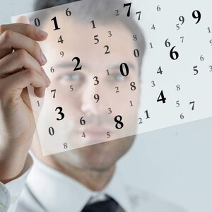 May include: A person holds a sheet of paper with a grid of numbers printed on it. The numbers are arranged in a random pattern. The person's face is blurred in the background.