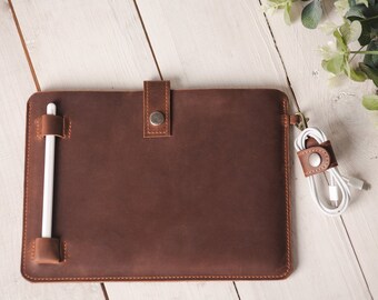 May include: A brown leather case with a flap closure and a white stylus holder. The case has a white cord holder with a button closure.