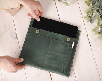 May include: A green leather tablet sleeve with a flap closure and a pocket for a stylus. The sleeve is open and a tablet is visible inside.