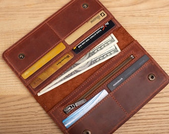 Puede incluir: Una cartera de cuero marrón con múltiples ranuras para tarjetas y un compartimento con cremallera. La cartera está abierta y contiene varias tarjetas de crédito, dinero en efectivo y una tarjeta azul con la palabra "monobank" impresa en ella.