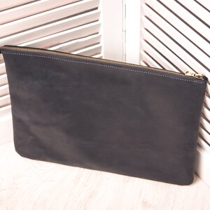 May include: A black leather zippered pouch with a gold zipper.