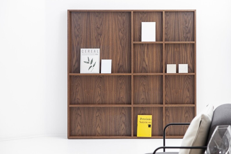 May include: A wooden bookshelf with nine shelves, featuring a magazine titled "Cereal" and a yellow book titled "Petronio Santoro" on the bottom shelves.