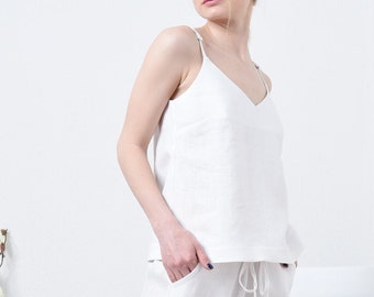 Peut inclure: Un haut de réservoir en lin blanc et un pantalon assorti. Le haut de réservoir a un col en V et le pantalon a une taille à cordon.