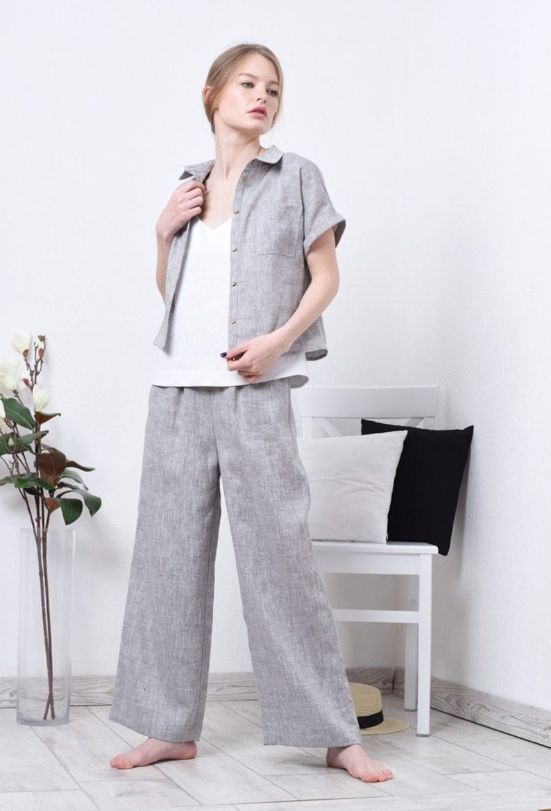 May include: A woman wearing a gray linen shirt and matching wide-leg pants. The shirt has a collar and short sleeves. The pants have a relaxed fit and are cropped at the ankle.