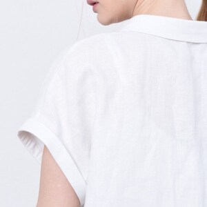 May include: White linen shirt with a collared neckline and short sleeves. The shirt has a relaxed fit and a casual style.