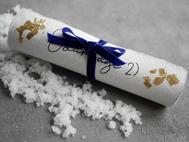 May include: A white scroll tied with a blue velvet ribbon, decorated with gold leaf accents. The scroll is labelled "Page 2".