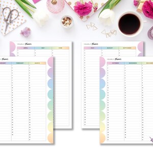 May include: Two yearly planner pages with a white background. The pages have a pastel rainbow color scheme. The text "Yearly Planner" is at the top of each page. The pages are open to January, February, March, April, May, June, July, August, September, October, November, and December.