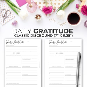 May include: A black and white printable daily gratitude journal with a classic discbound design. The journal is 17.8 cm by 23.5 cm and features sections for daily affirmations, a mood tracker, a quote of the day, things you are grateful for, lessons learned, a happy memory, and a good thing that happened today.