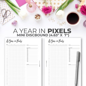 Puede incluir: Una página de planificador imprimible titulada "A Year in Pixels" con una cuadrícula de cuadrados y una columna para objetivos diarios. La página está diseñada para un planificador mini discbound y mide 11,76 cm por 17,78 cm.