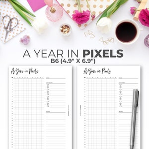 May include: Two white B6 (4.9" x 6.9") "A Year in Pixels" planner pages with grid layouts for tracking habits. The pages are surrounded by flowers, stationery, and a cup of coffee. The text "A YEAR IN PIXELS" is at the top.