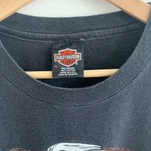 May include: Black t-shirt with a Harley-Davidson logo and an eagle graphic. The tag says "Pre-shrunk 100% Cotton Made in U.S.A. Care on Reverse".