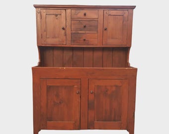 May include: A rustic, wooden hutch with a warm, reddish-brown finish. The upper section features two cabinet doors and three small drawers. The lower section has two larger cabinet doors. This antique-style cabinet is perfect for storage.