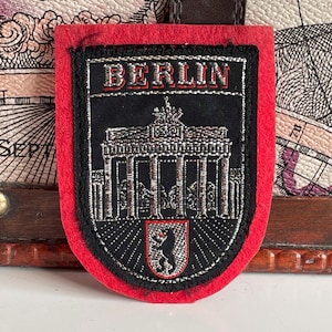 Könnte beinhalten: Ein Set aus drei Keramikbechern mit gesprenkelter, matter Oberfläche. Die Becher sind in Creme-, Hellgrau- und Dunkelgrautönen gehalten. Jeder Becher hat ein schlichtes, minimalistisches Design.