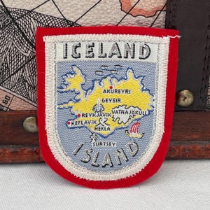 May include: A red-edged patch displaying "ICELAND" at the top. The patch shows a map of Iceland, highlighting cities such as Reykjavik and Akureyri. The word "ISLAND" is at the bottom.