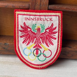 Könnte beinhalten: Eine weiße Keramik-Tasse mit schwarzem Henkel und dem Text "But First, Coffee" in schwarzer, handschriftlicher Schrift. Die Tasse steht auf einer weißen Oberfläche.