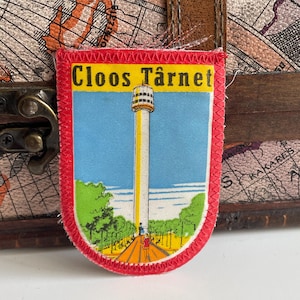 May include: A red, white, and blue embroidered patch with the text "Cloos Tårnet" and a depiction of a tall, yellow tower.